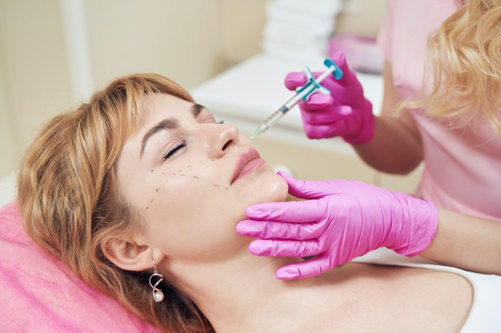 Charming female during the facial procedure with hyaluronic acid