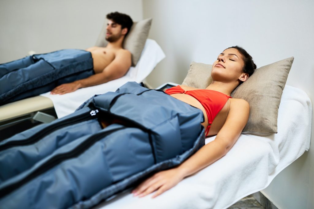 Young couple receiving pressotherapy at health spa.