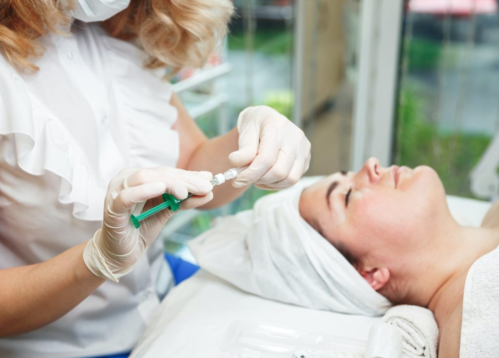 Young woman is getting a collagen injection in her face. Skin care